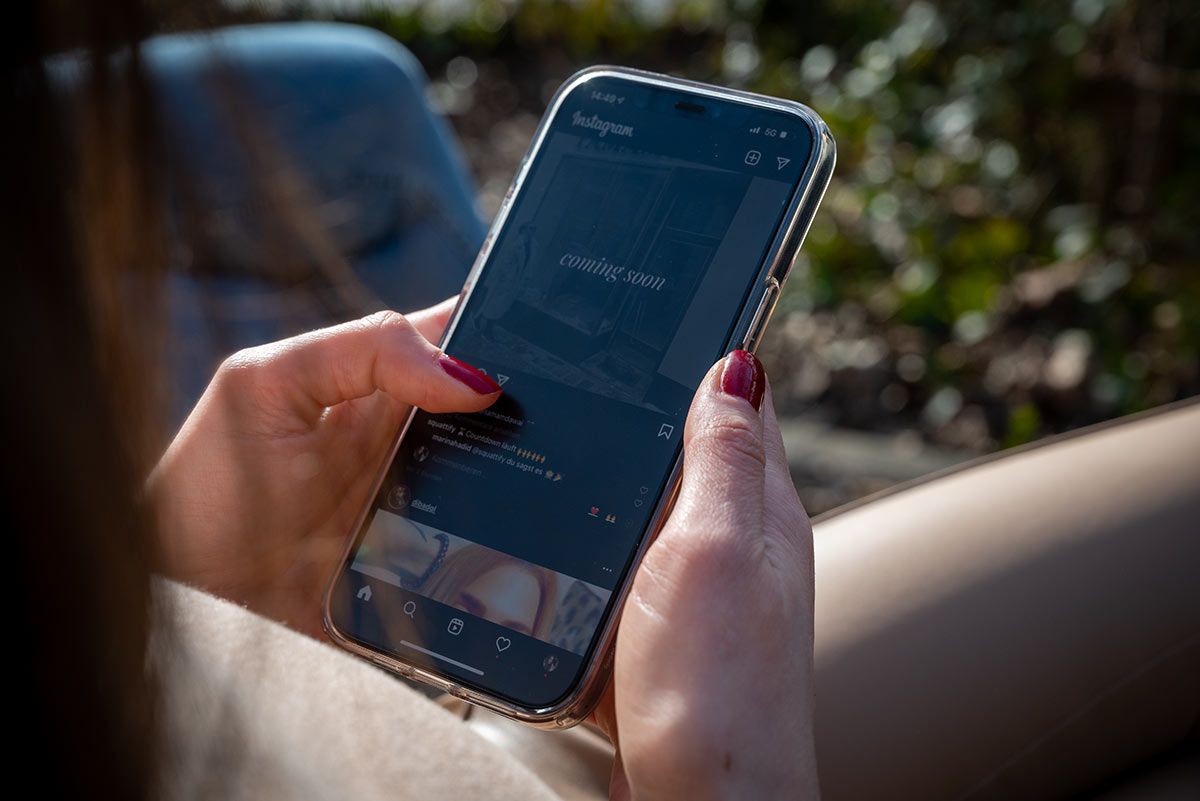 Frau mit Handy schaut sich einen Social Media Kanal an